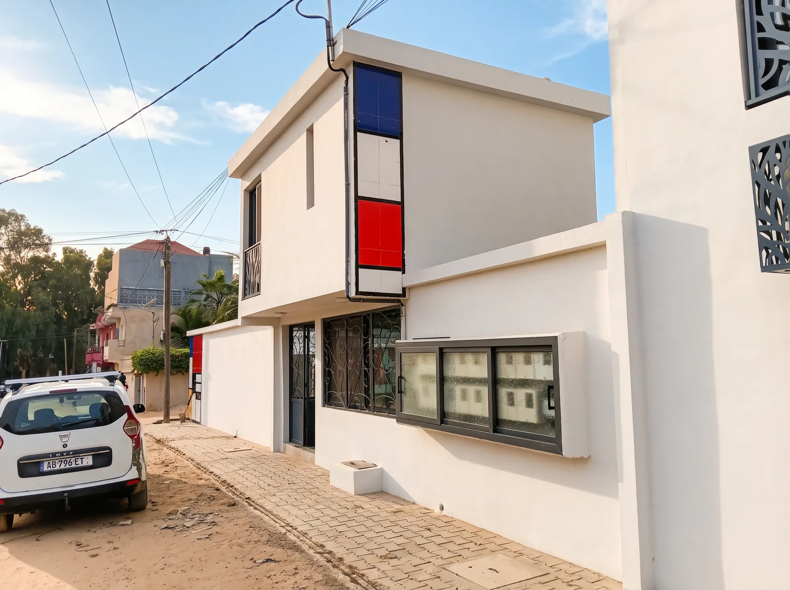 Façade du Mondrian vue depuis la rue : mur blanc, bandeau vertical bleu, blanc et rouge, et baie vitrée.